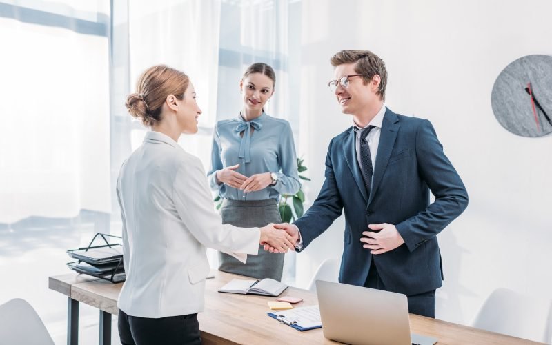 cheerful-recruiter-shaking-hands-with-woman-near-colleague-in-office.jpg